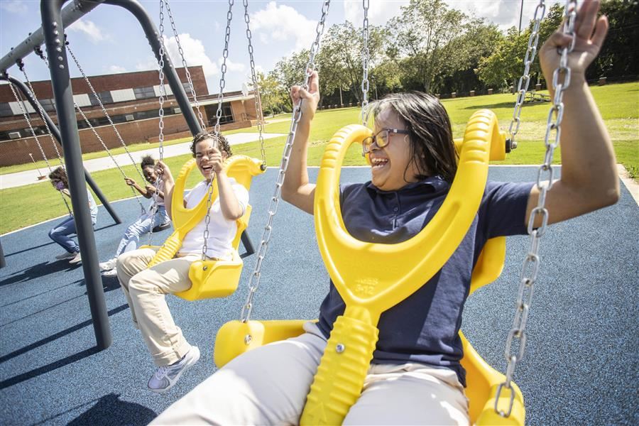 Four students swinging with big smiles on their faces.